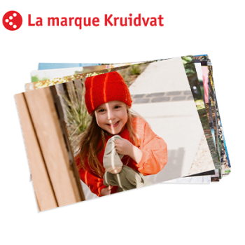 Une fille souriante porte un bonnet rouge et un pull orange, tenant une peluche dehors au soleil